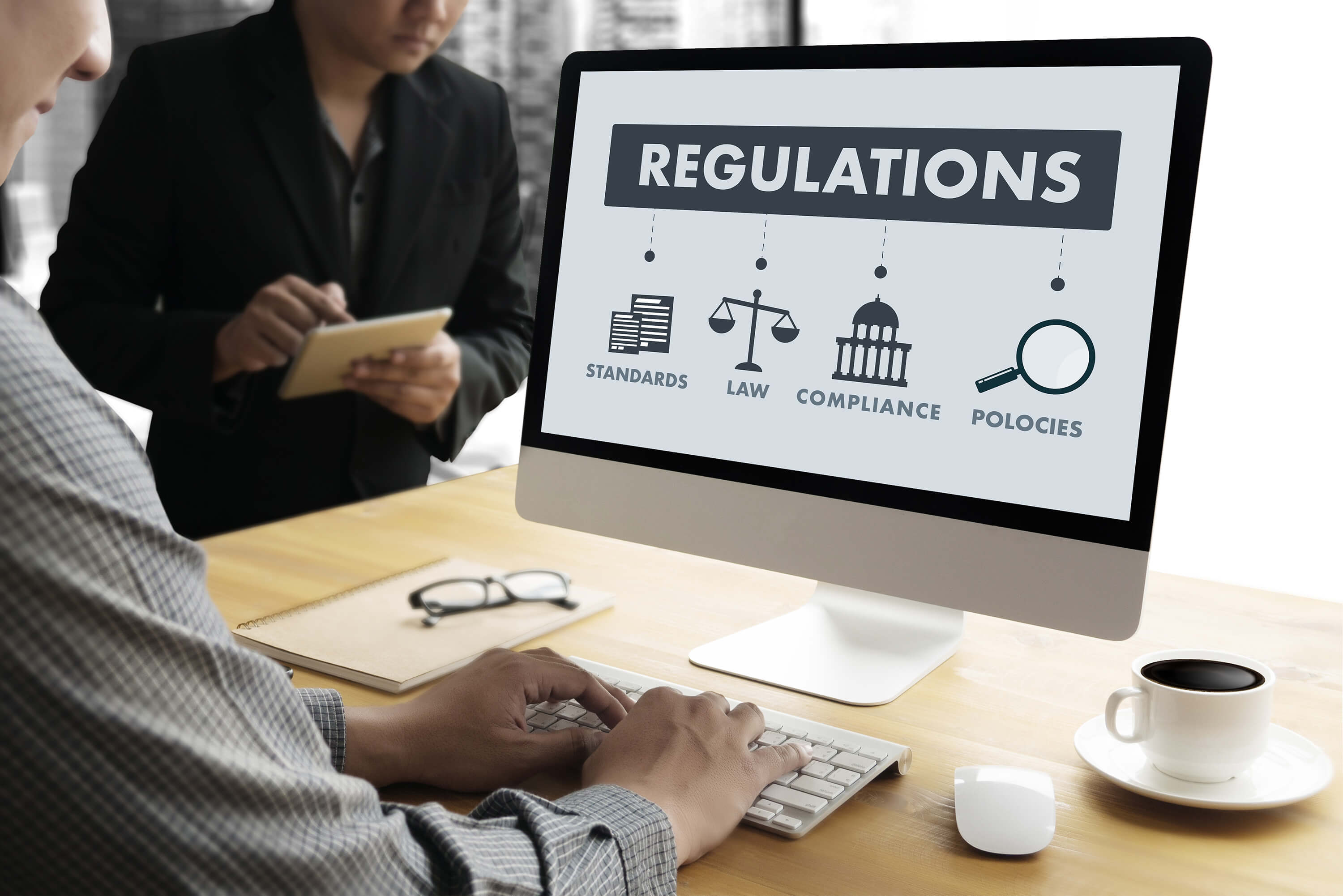 A person works at a computer displaying regulations and compliance information.