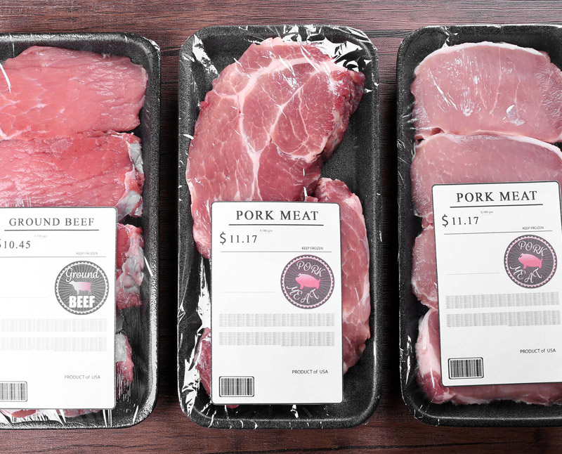 Packed pork and beef cuts are arranged on a wooden background.