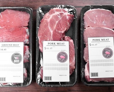 Packed pork and beef cuts are arranged on a wooden background.