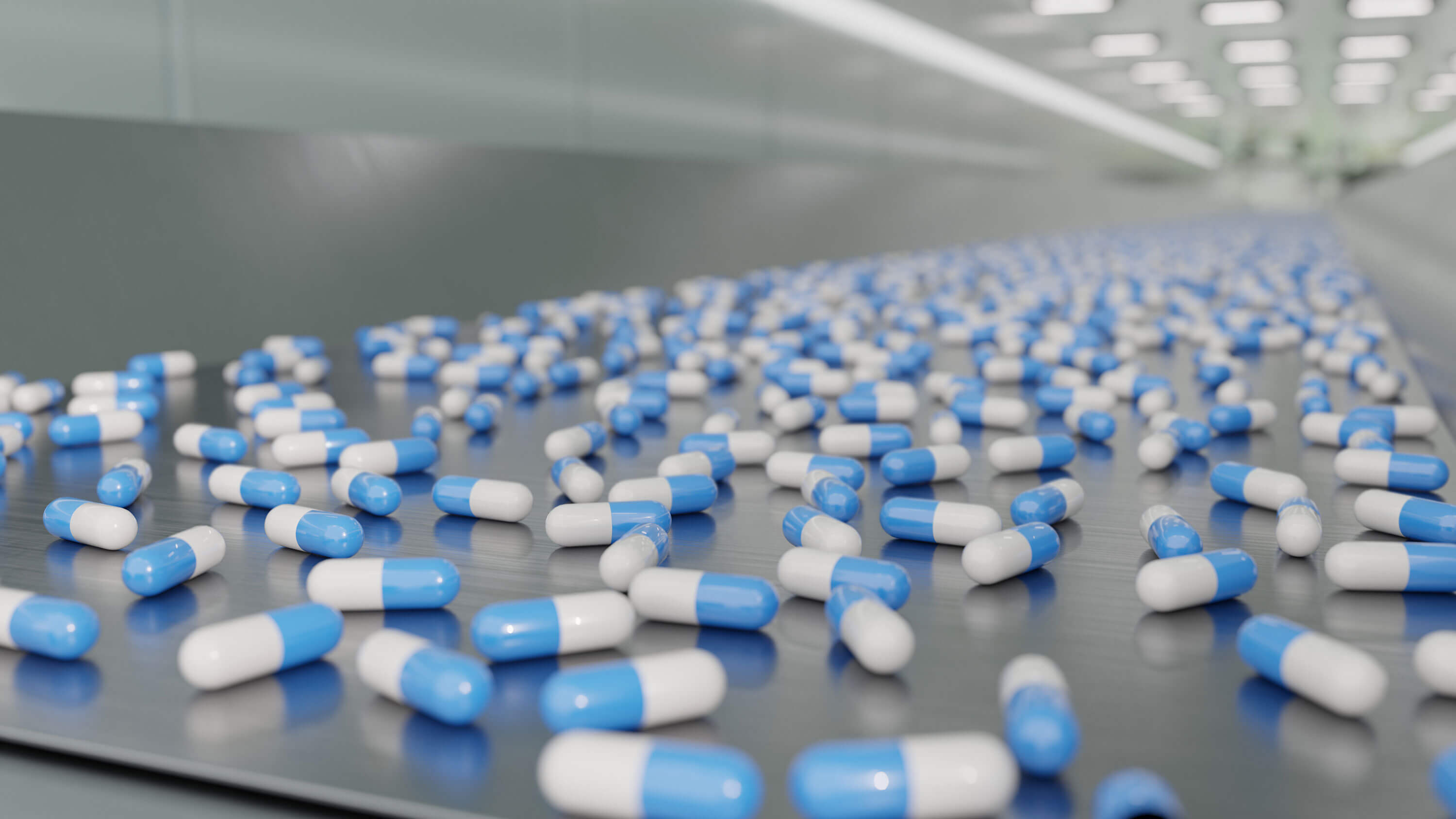 Production line with rows of blue capsules in a pharmaceutical manufacturing facility.