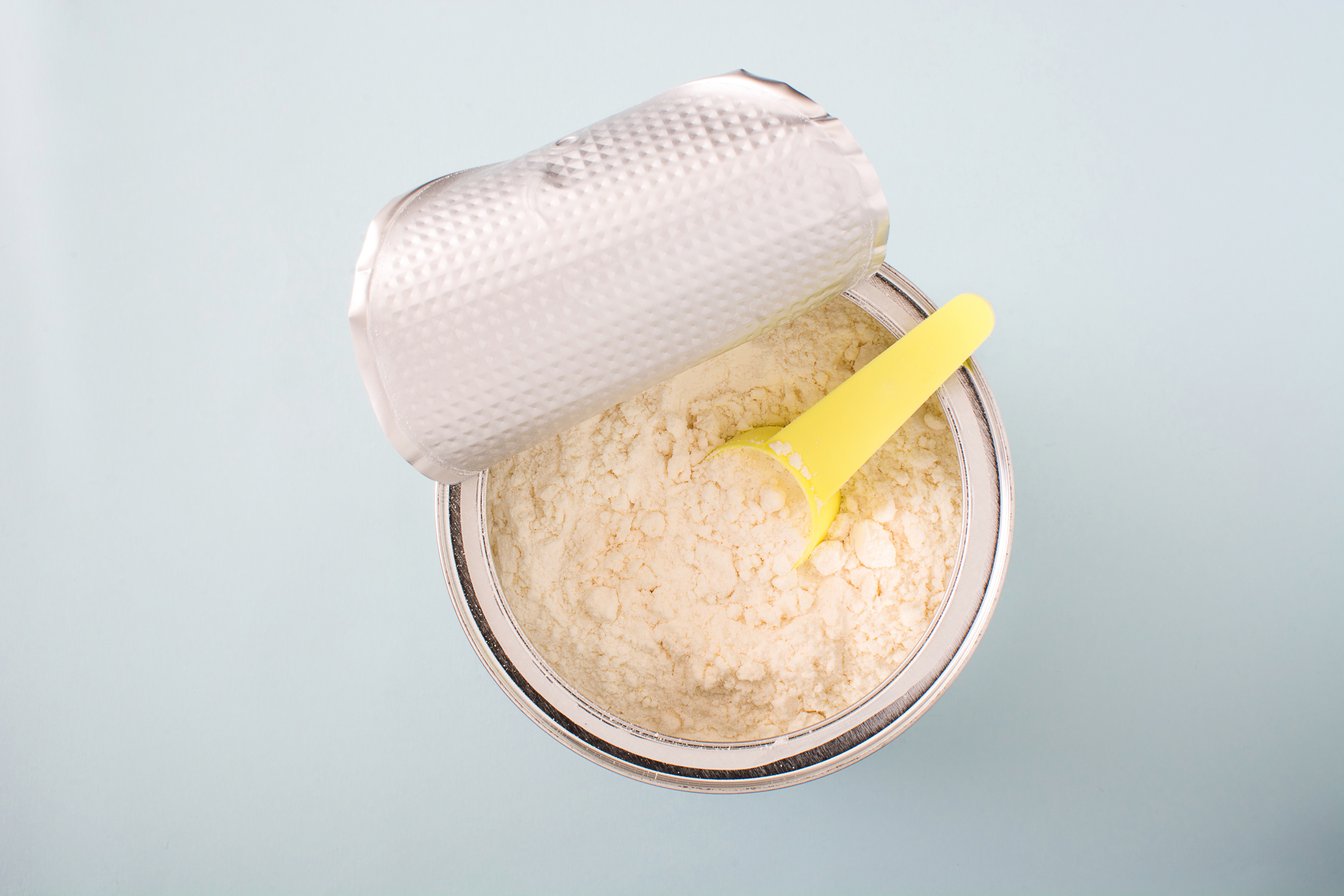 Powdered infant formula in a container with measuring Scoop.