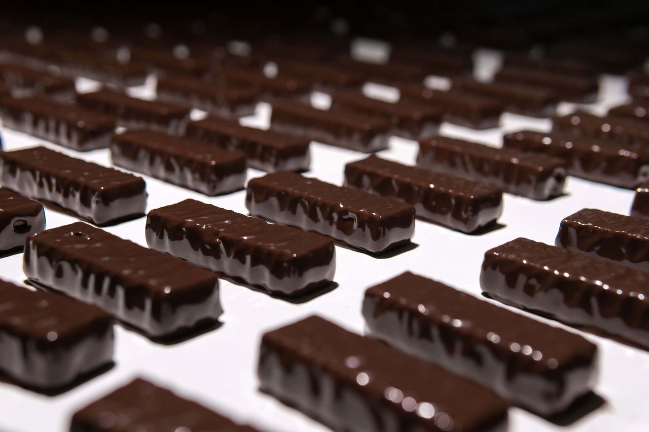 Close-up of chocolate candies moving along a conveyor belt in a confectionery factory.