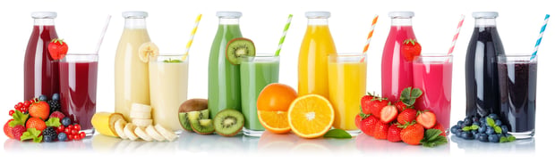 A collection of fruit juice bottles and glasses is arranged on a white background.