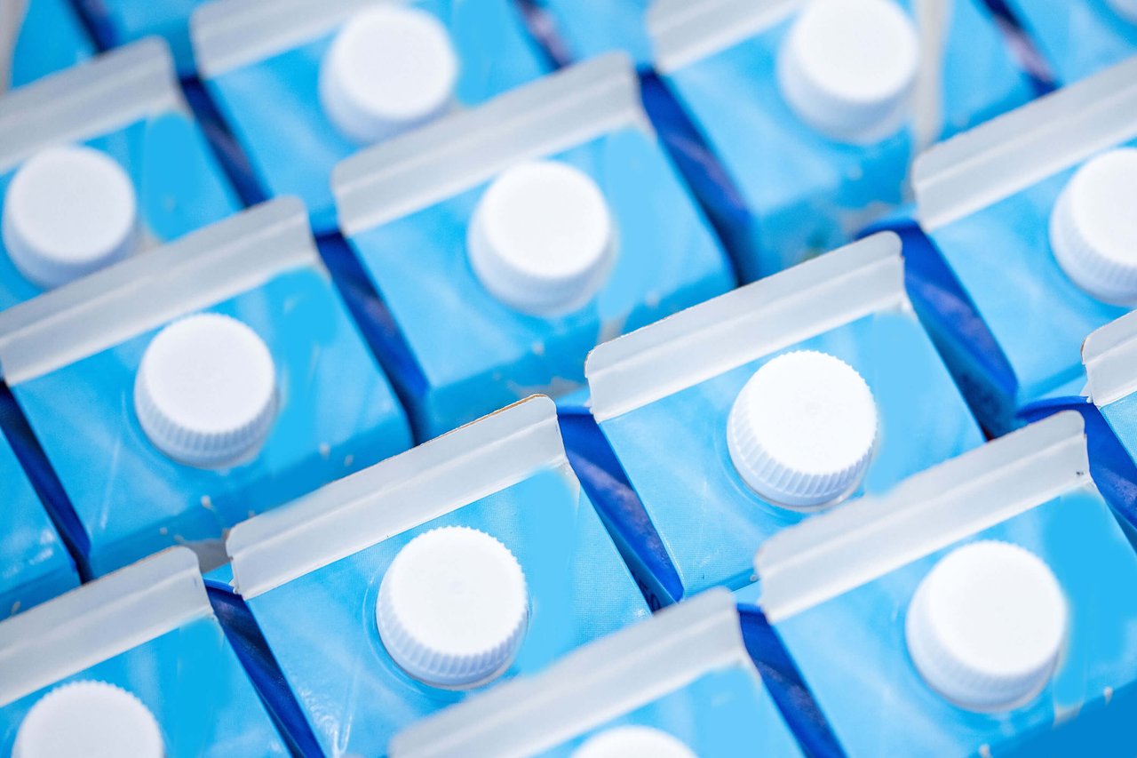 Blue milk cartons are lined up in rows on a production line.