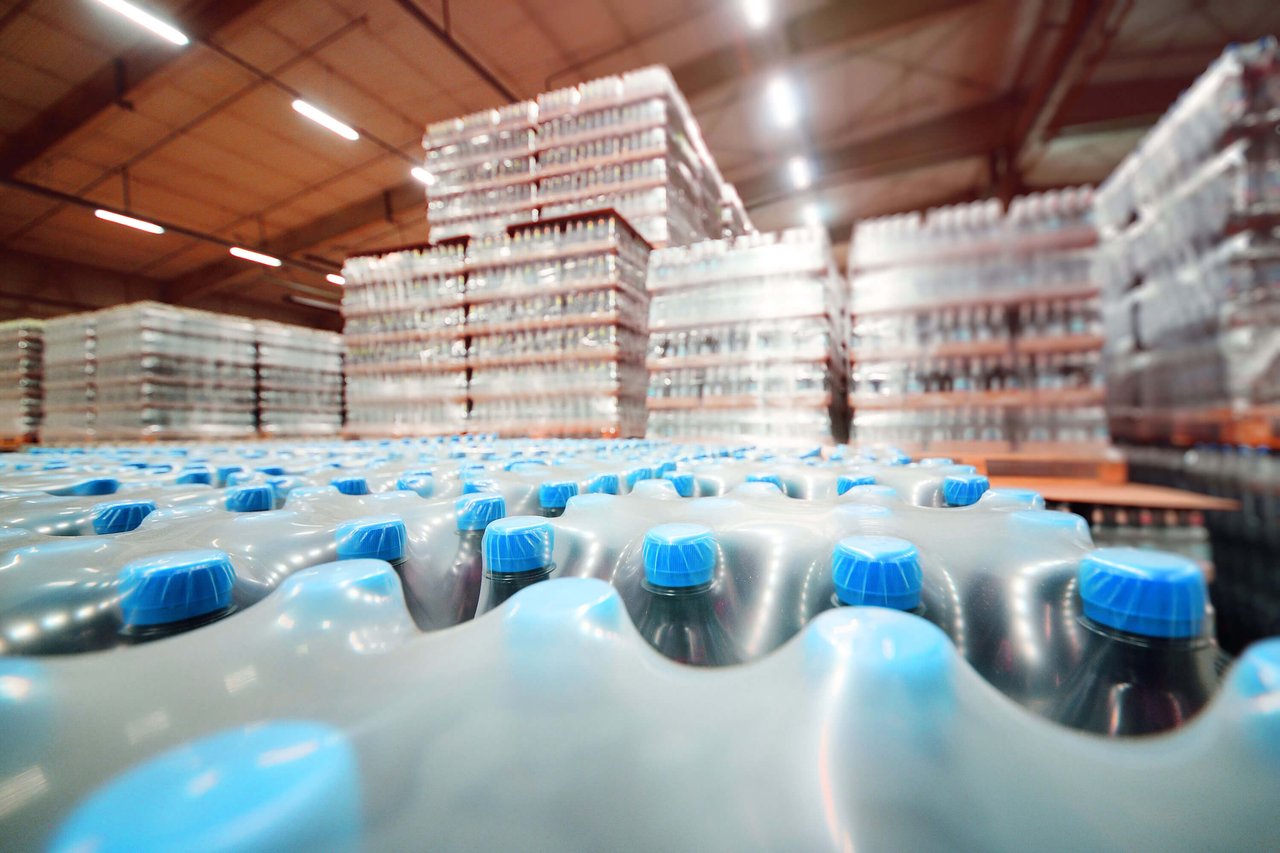 An industrial warehouse stores packaged beverages in plastic bottles.