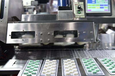 Silver aluminum blister packs move along a pharmaceutical production line.