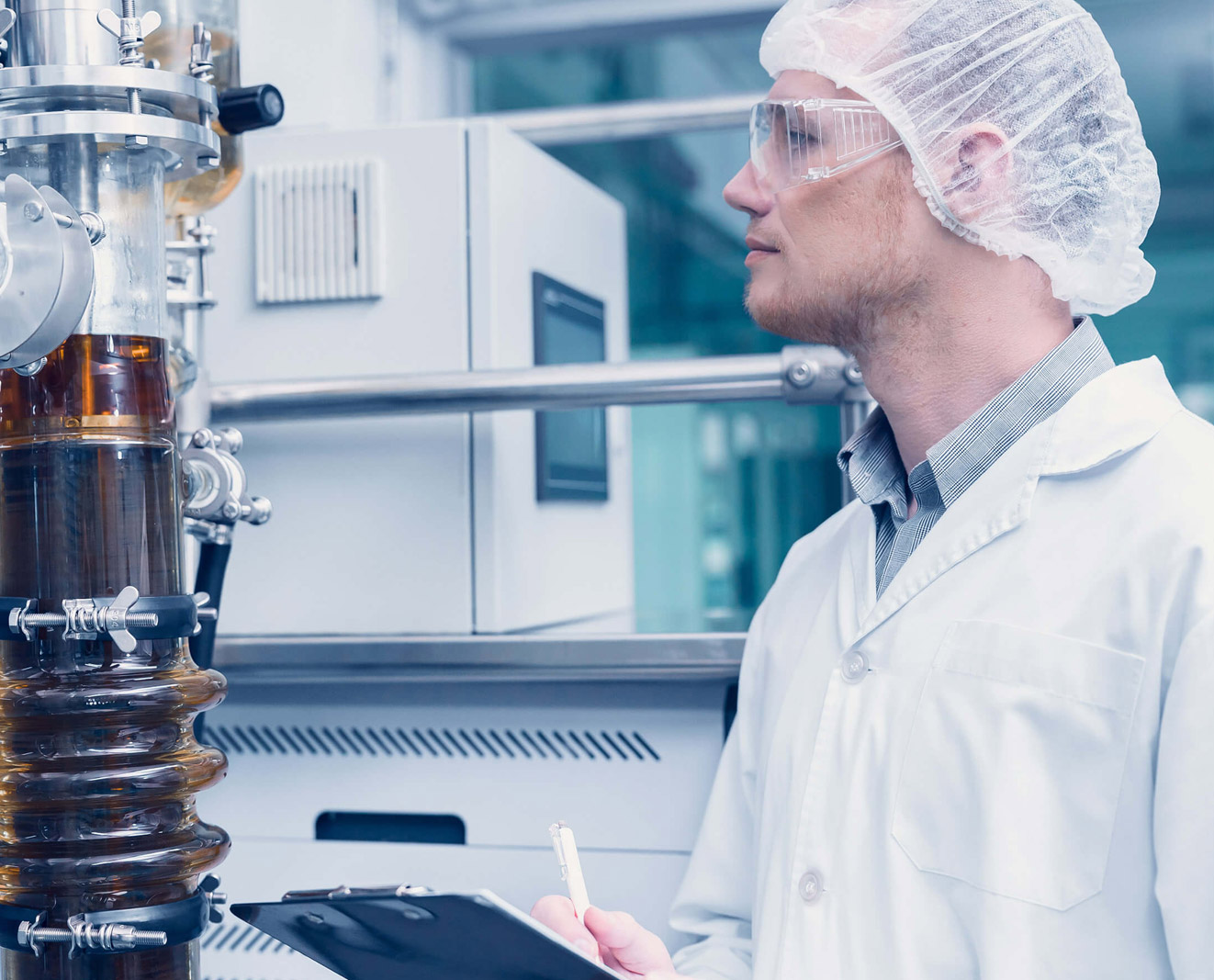 A worker operates an oil extraction machine in a laboratory production setting.