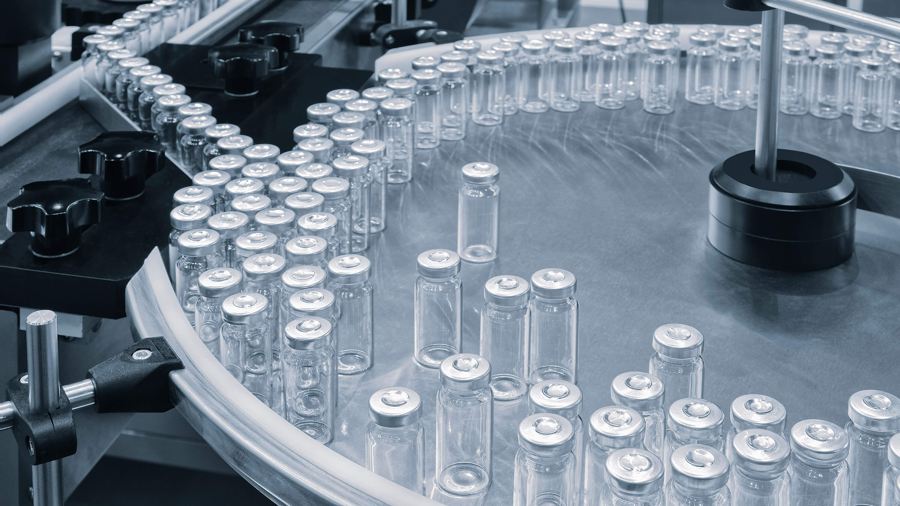 Glass ampoules move along a machine conveyor on a pharmaceutical production line.