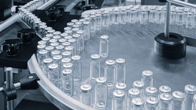 Glass ampoules move along a machine conveyor on a pharmaceutical production line.