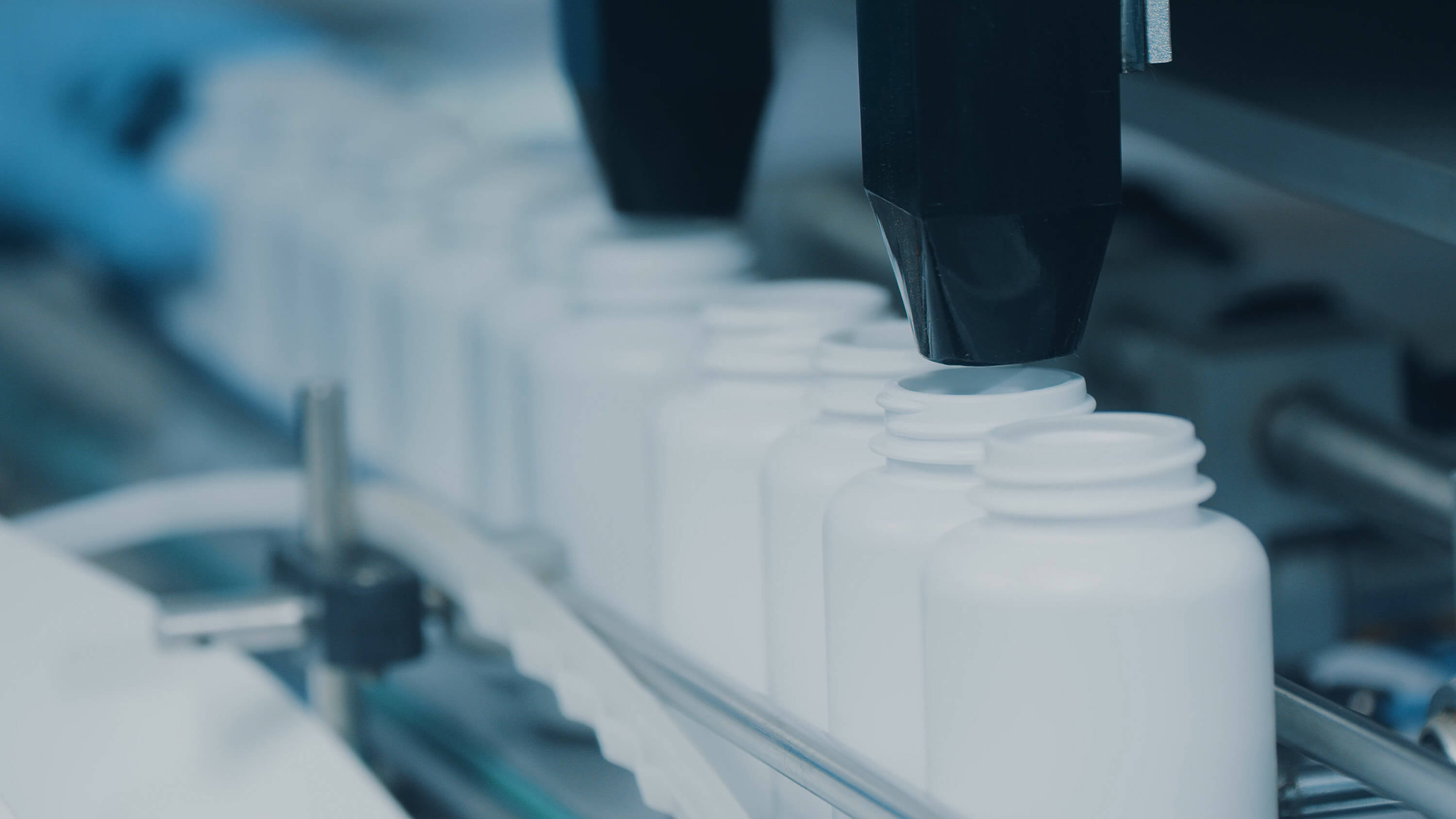White plastic tubes move along a production line as capsules are filled into them in a modern pharmaceutical factory.