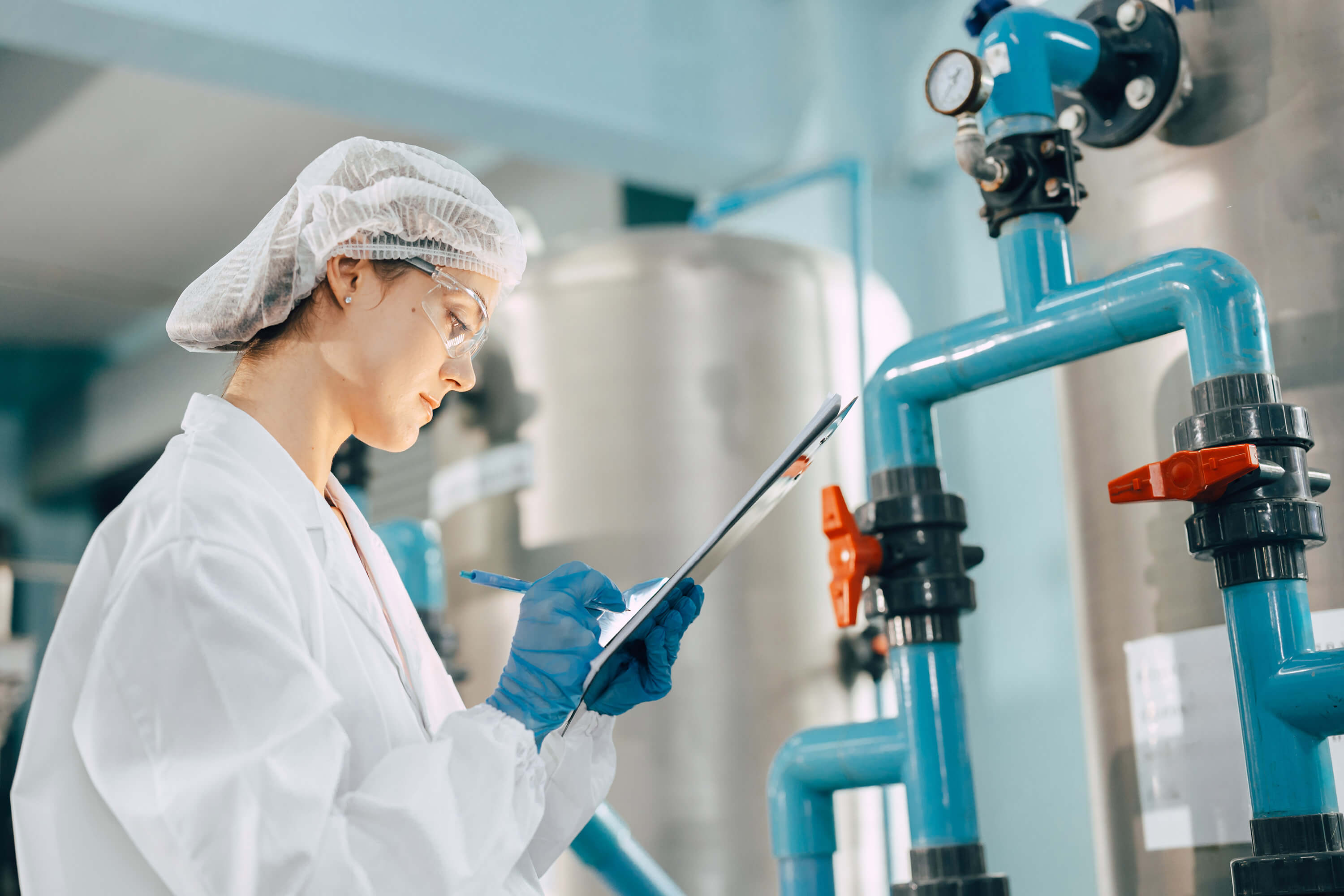 A factory worker monitors valves and water pipes during the drinking water purification process.