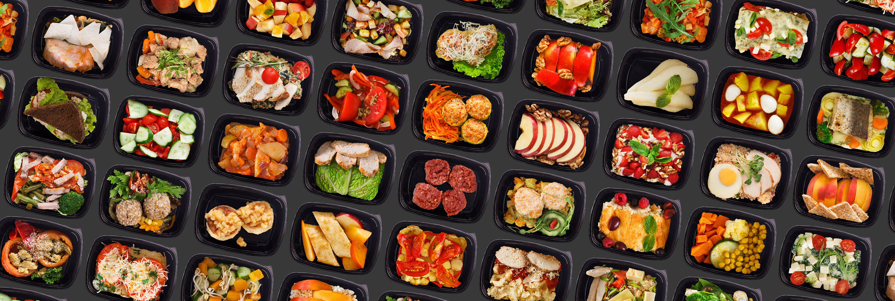 Take-away lunch boxes filled with prepared healthy meals on a black background.