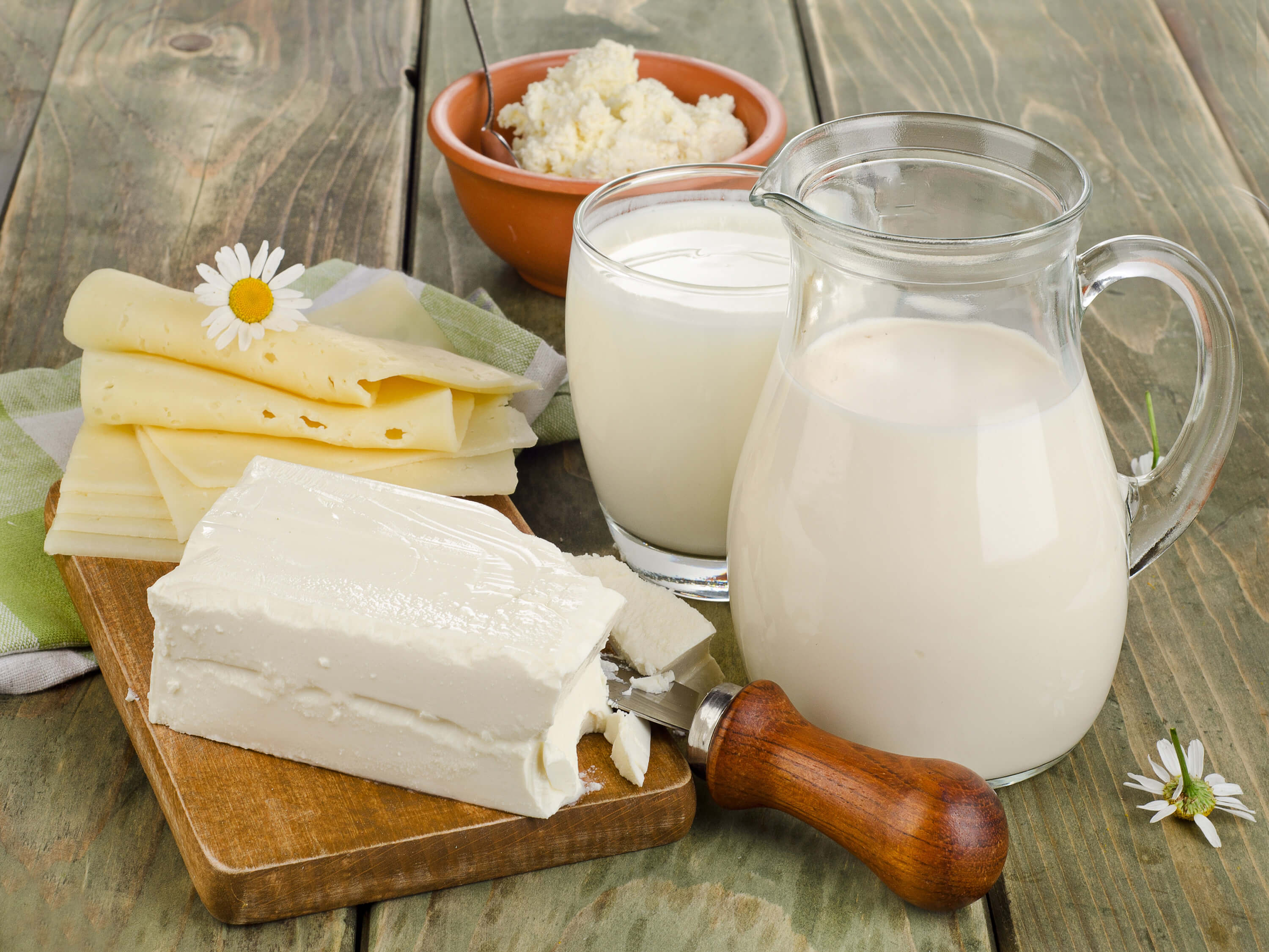 Dairy products such as milk and cheese on a wooden table.