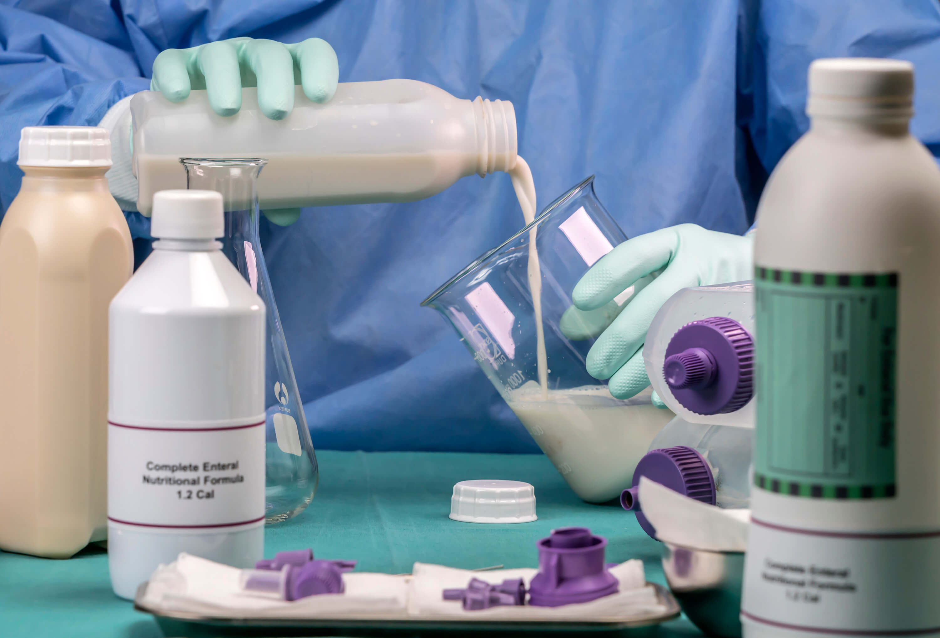 Nurse preparing enteral nutrition formula in a hospital care setting.