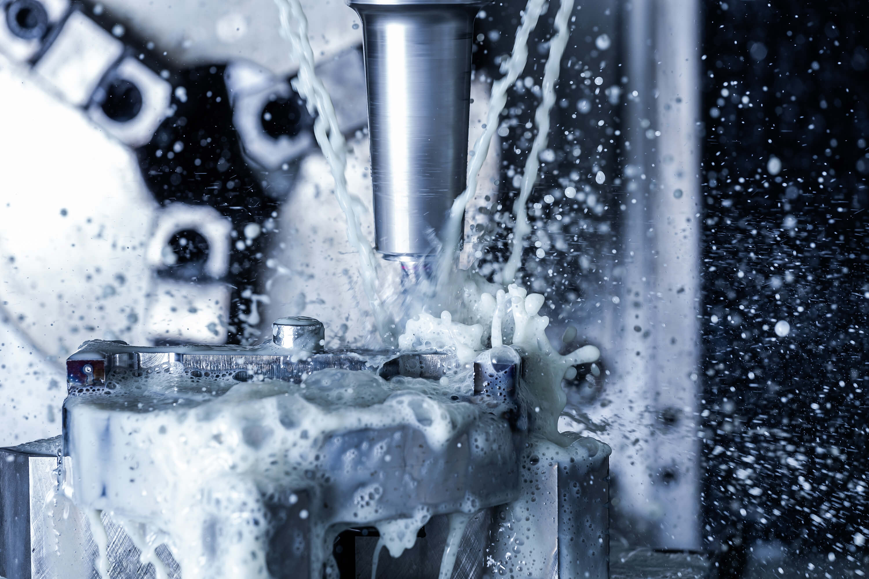 Vertical CNC steel milling with water coolant streams and splashes.
