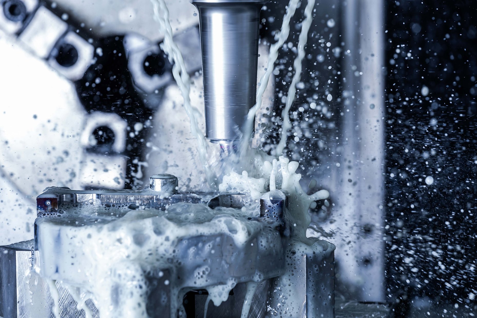 Vertical CNC steel milling with water coolant streams and splashes.