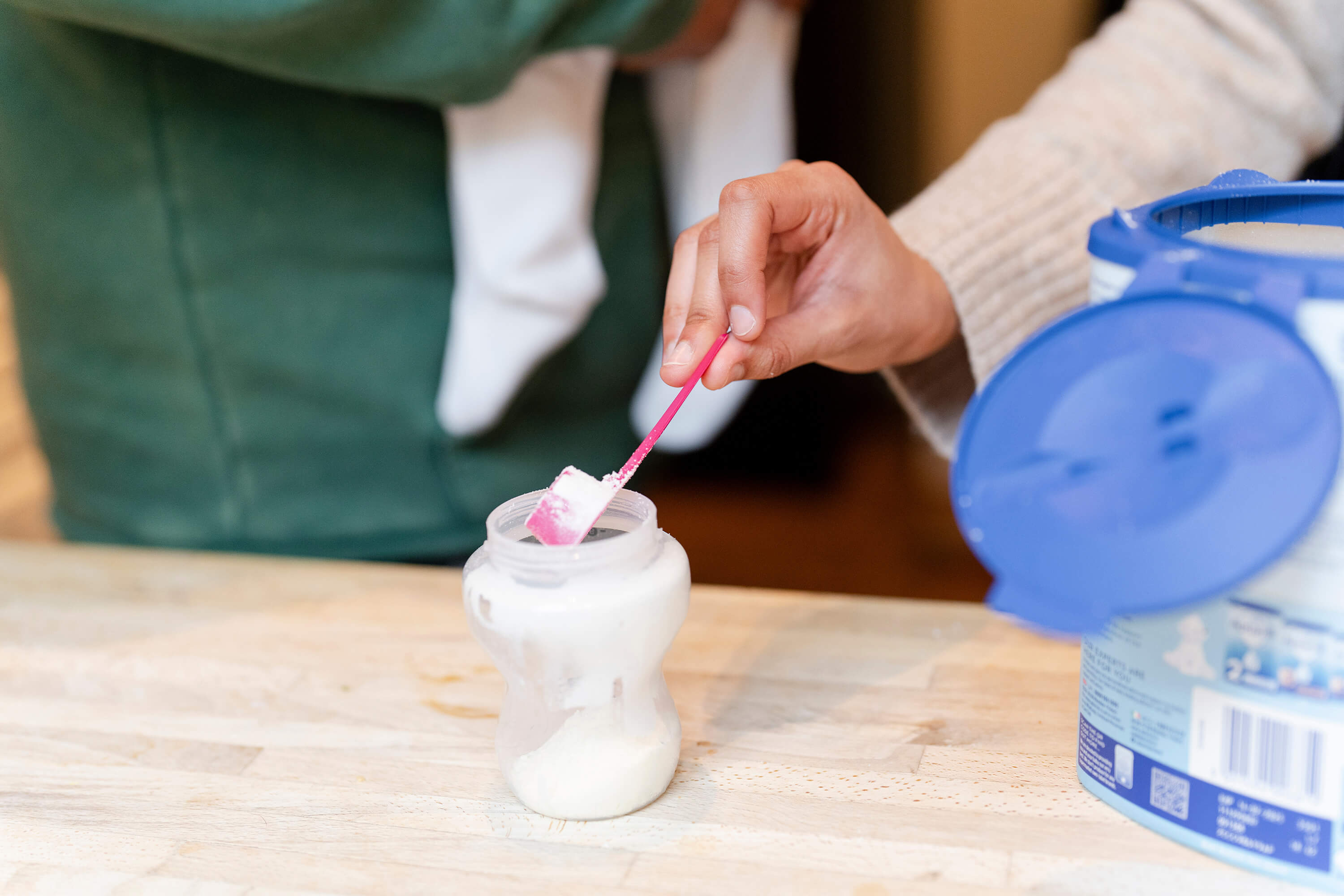 Mother preparing baby formula at home.