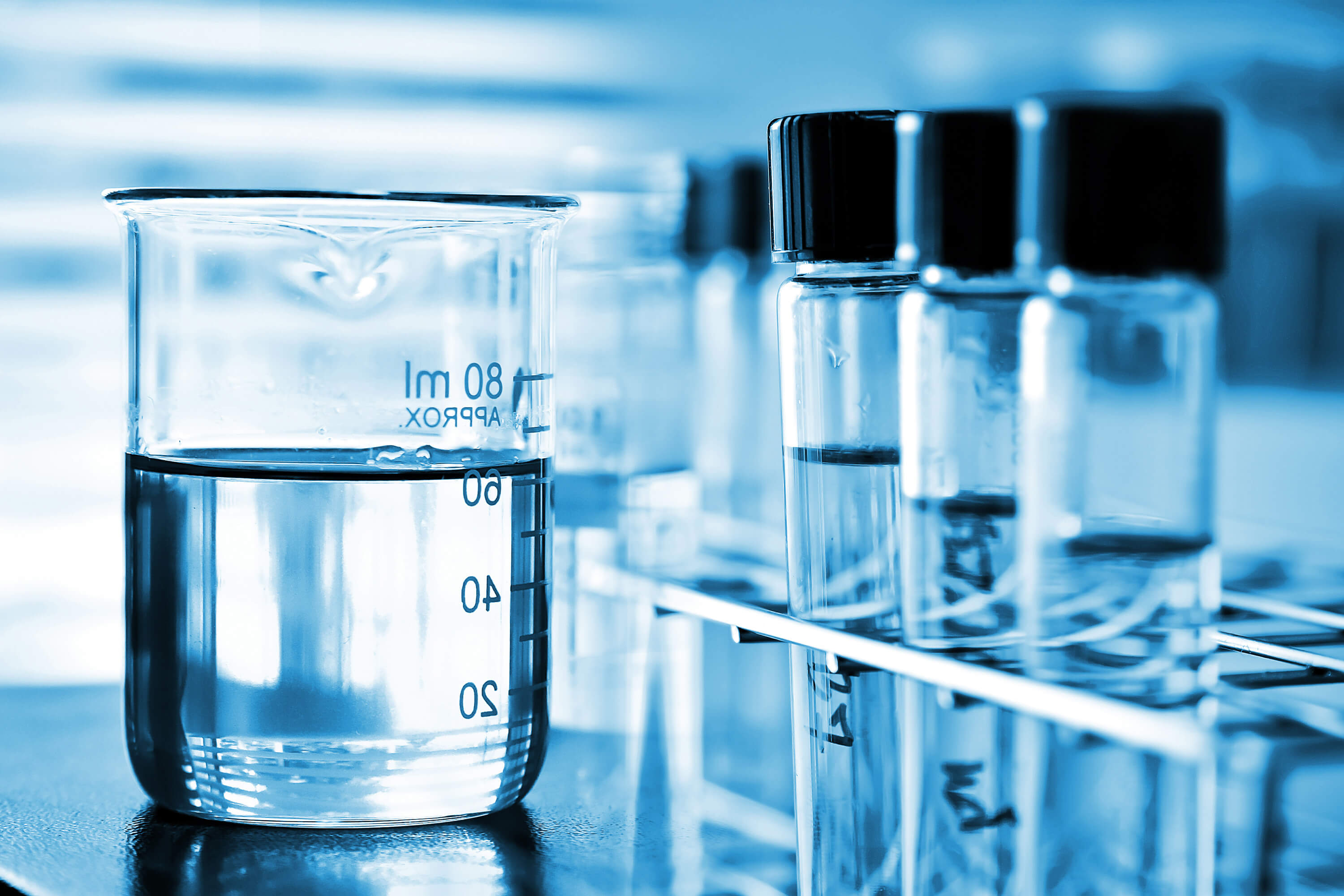 Beaker containing chemical liquid with sample vials in a laboratory.