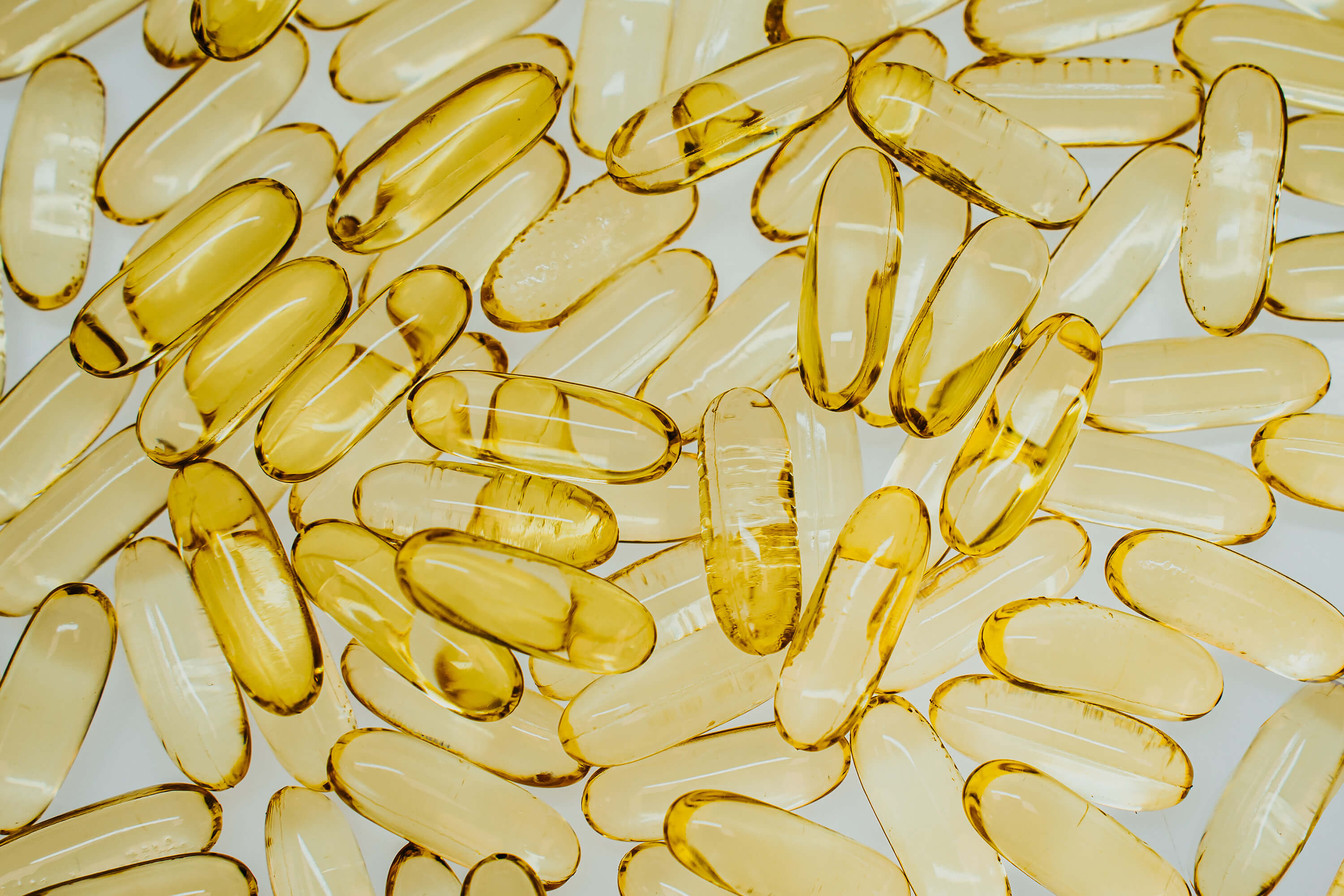 Yellow softgel supplement capsules as a close-up background.
