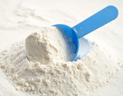 Blue scoop filled with powdered infant formula.