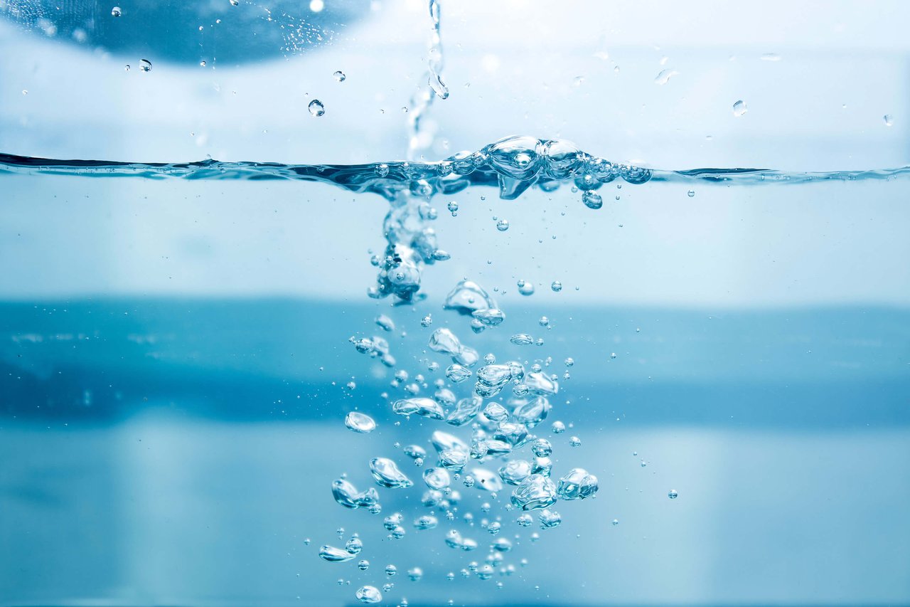 Water is poured into a glass, creating soap bubbles.