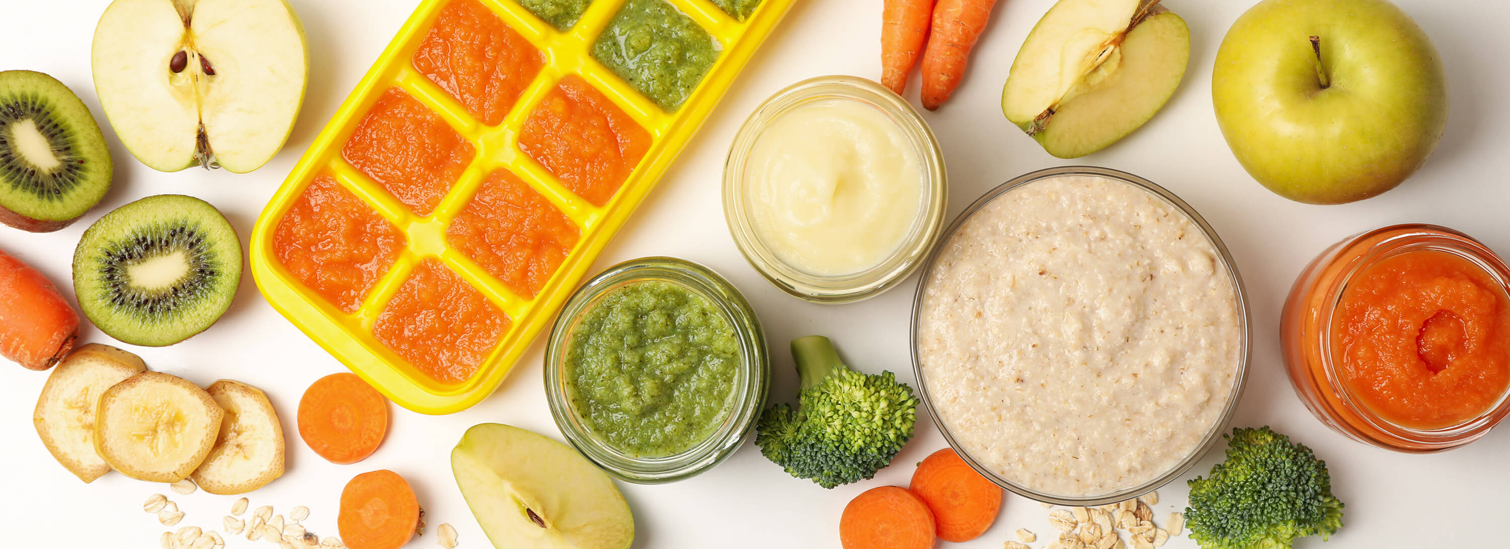 A top view of baby food with fruits and vegetables on a white background.