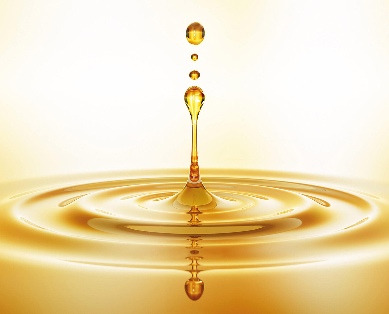 Golden oil drop on a vibrant yellow background, showcasing its glossy texture and rich color.
