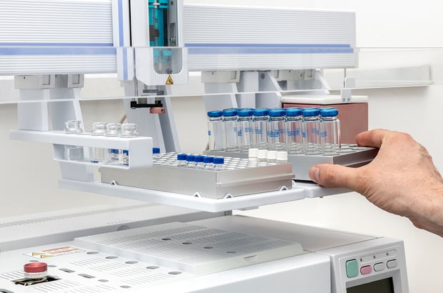 Laboratory autosampler tray being loaded with sample vials for chromatographic analysis.