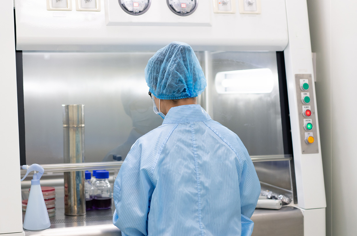 Technician performing aseptic sample handling in an isolator for pharmaceutical sterility testing.