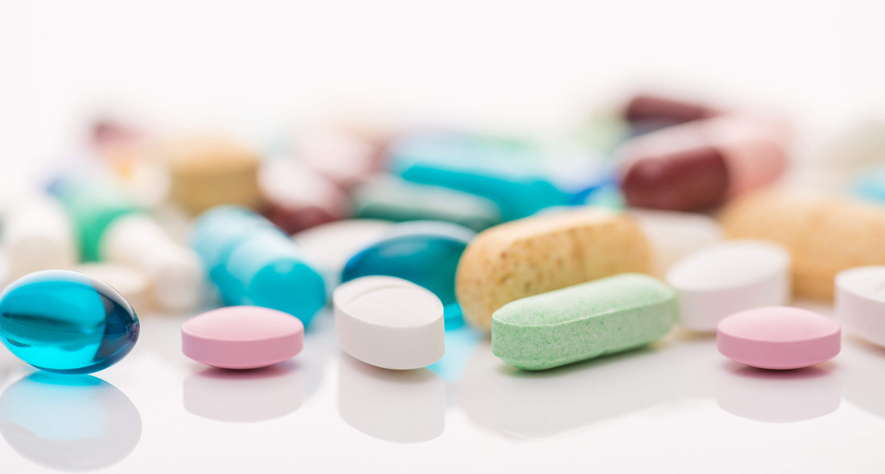 Various tablets and capsules are scattered on a light-colored surface.