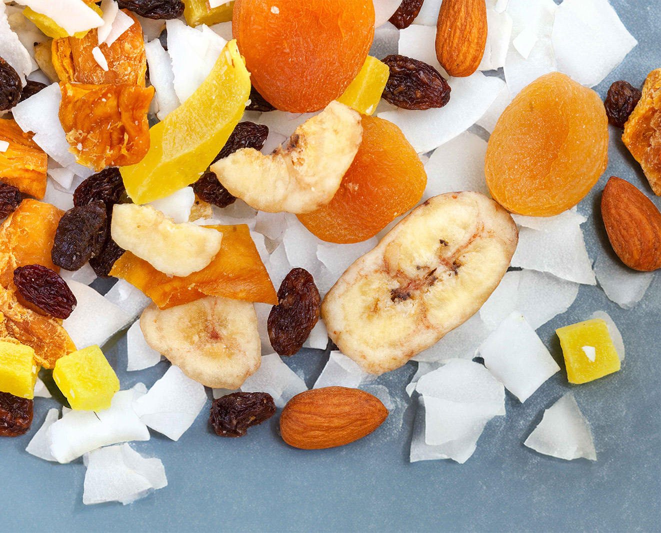 A vibrant pile of assorted dried fruits and nuts displayed on a blue background.