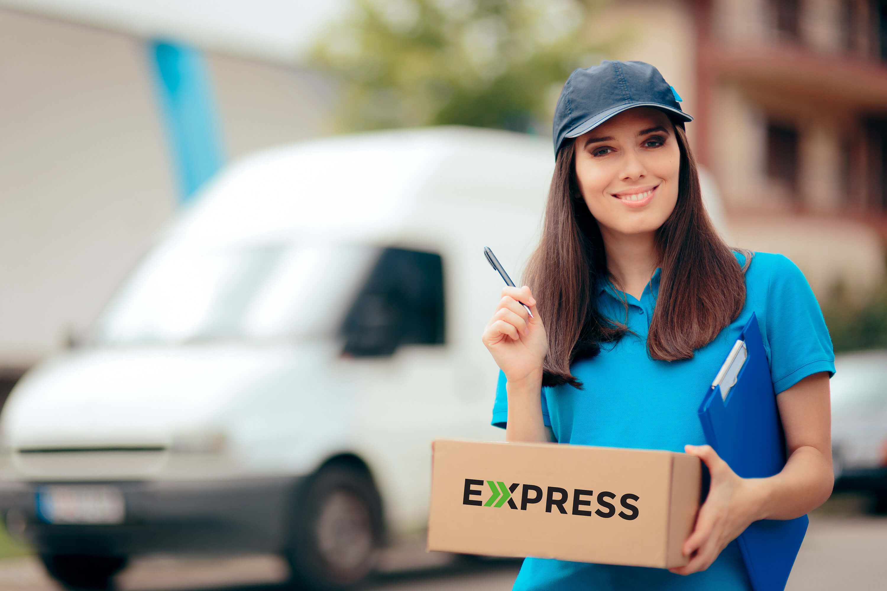 Delivery worker holding a package in front of a delivery van.