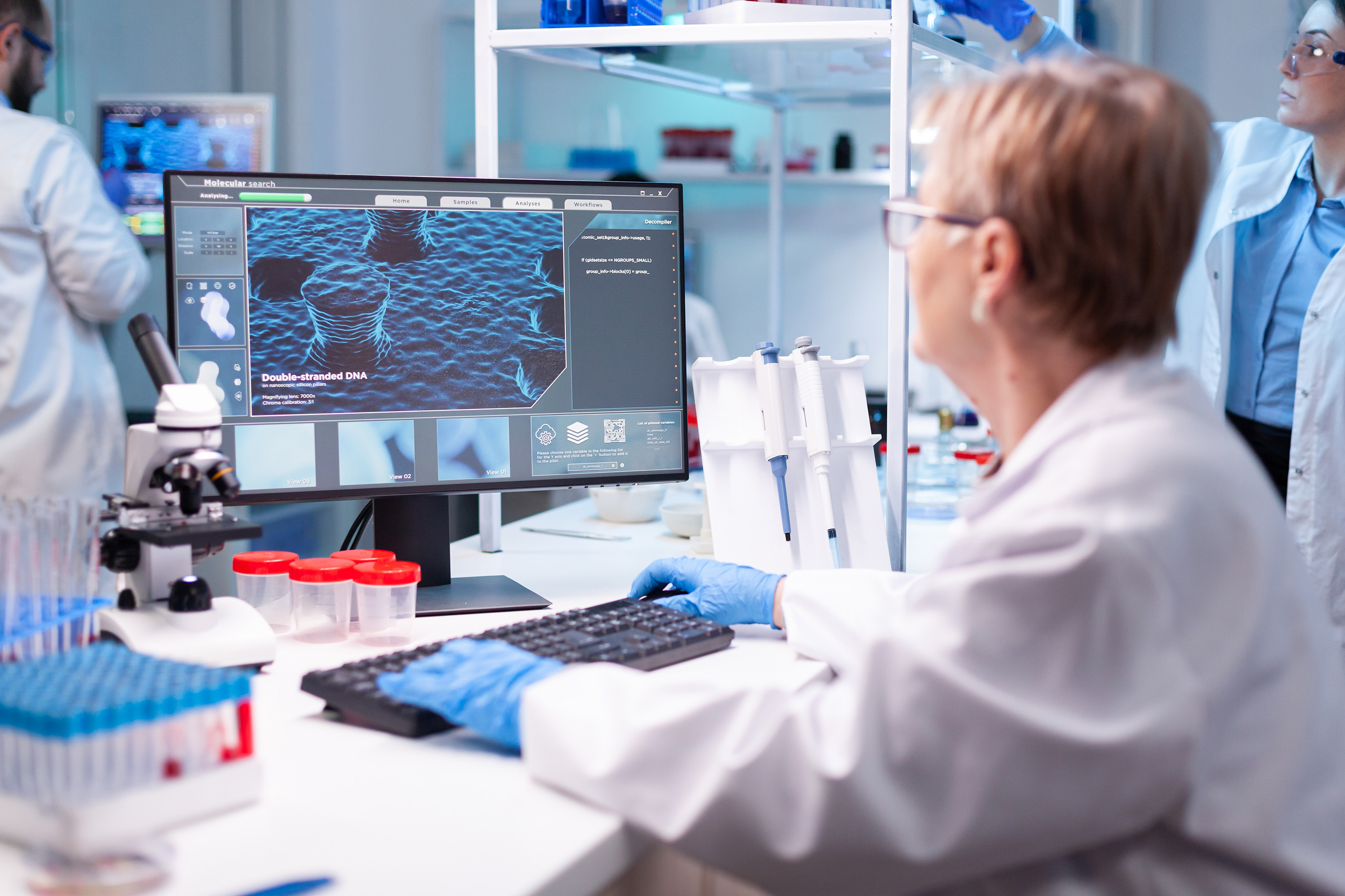 Scientists in a modern laboratory analyzing molecular data on a computer screen.