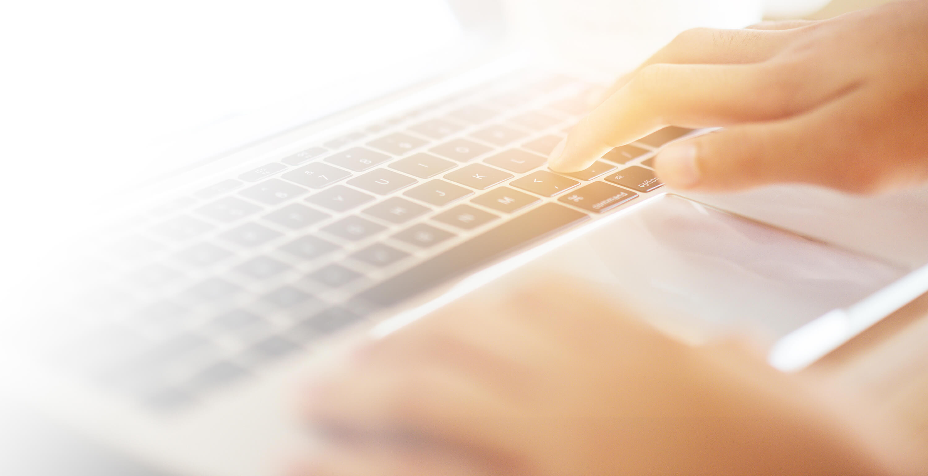 Hands type on a laptop keyboard in a close-up view.