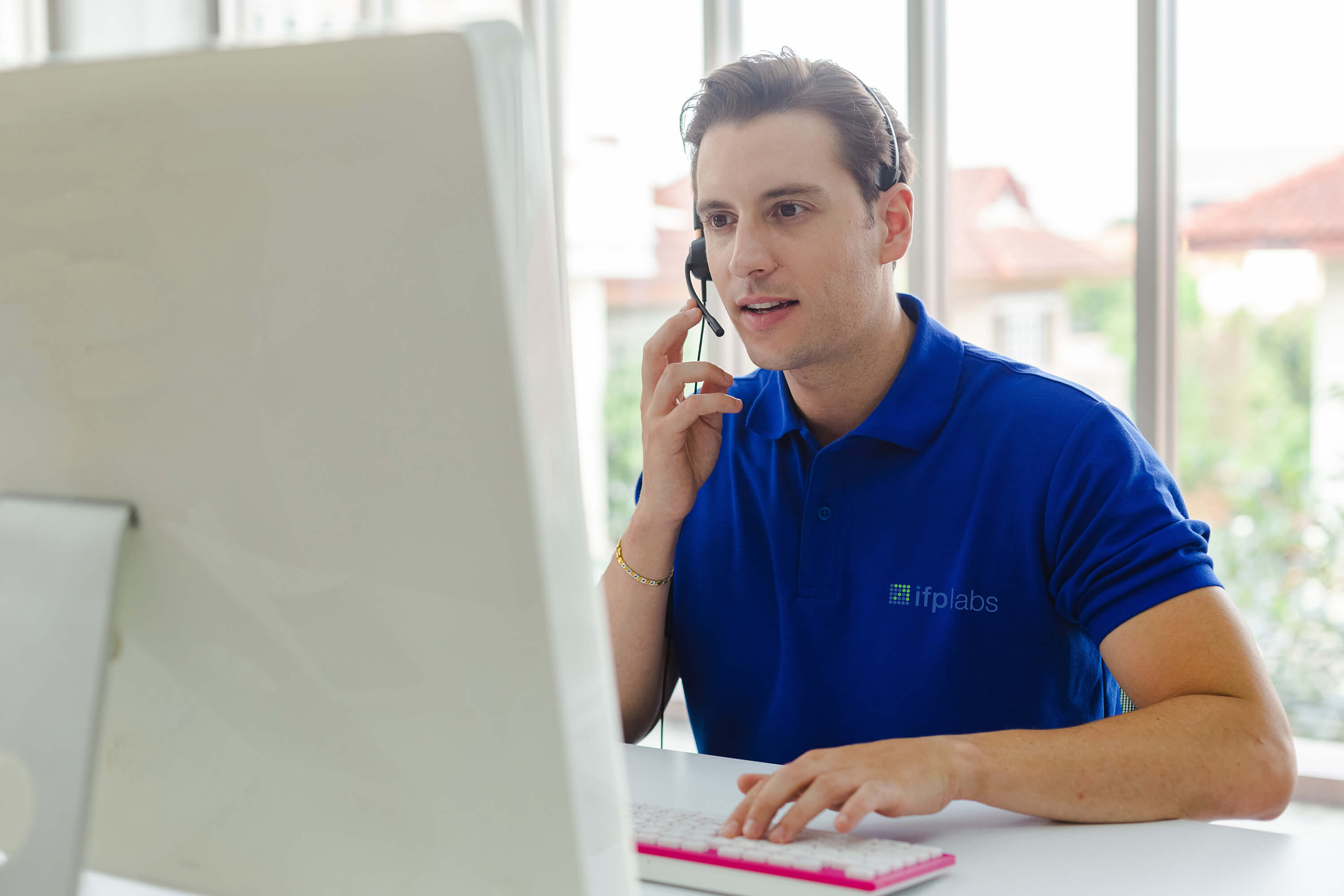 ifplabs employee wearing a headset while assisting a customer at a computer.