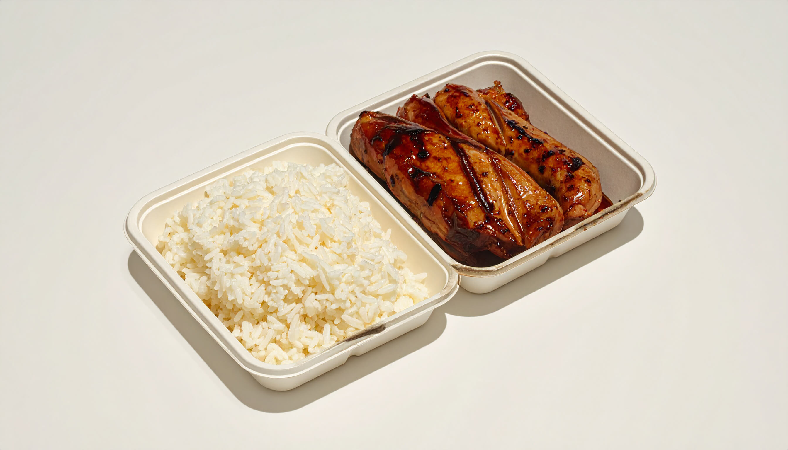 A meal tray contains white rice and glazed meat portions.