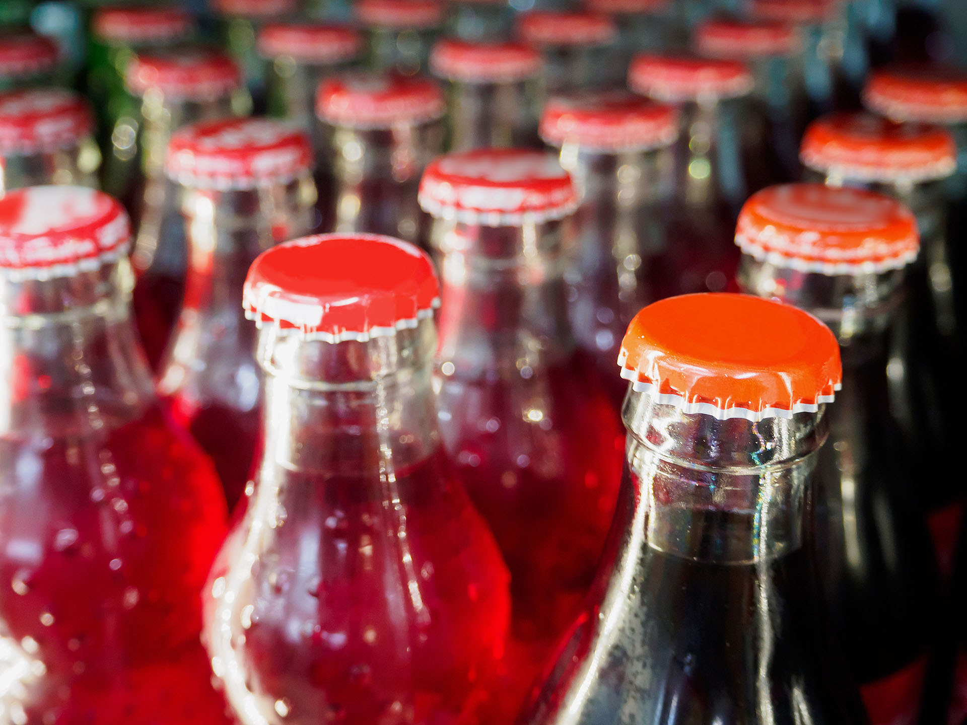 Glass bottles with red caps filled with beverages.