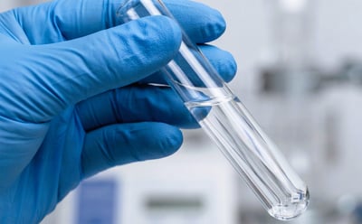 Scientist Hand Holding test tube with clear water liquid.