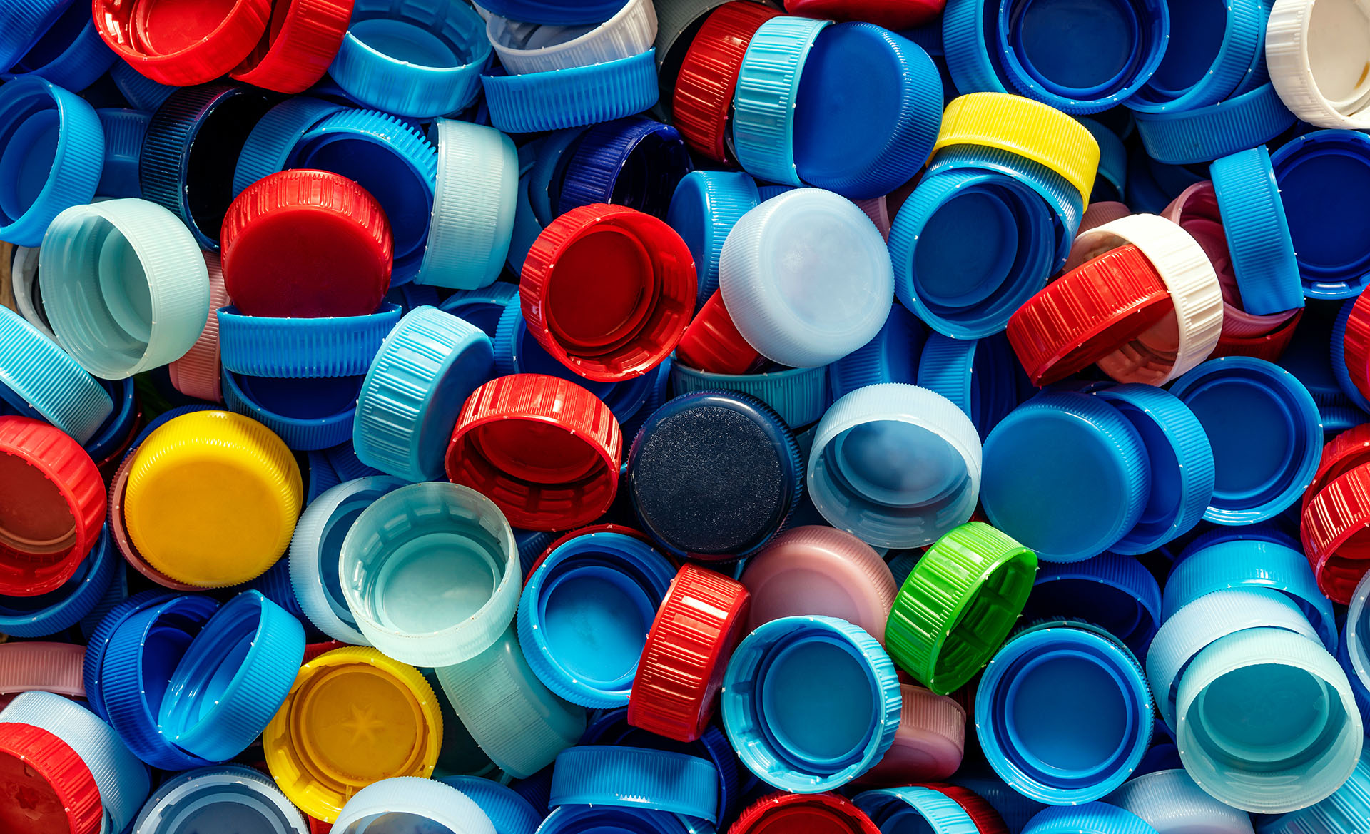 Mixed plastic bottle caps in various colors piled together.