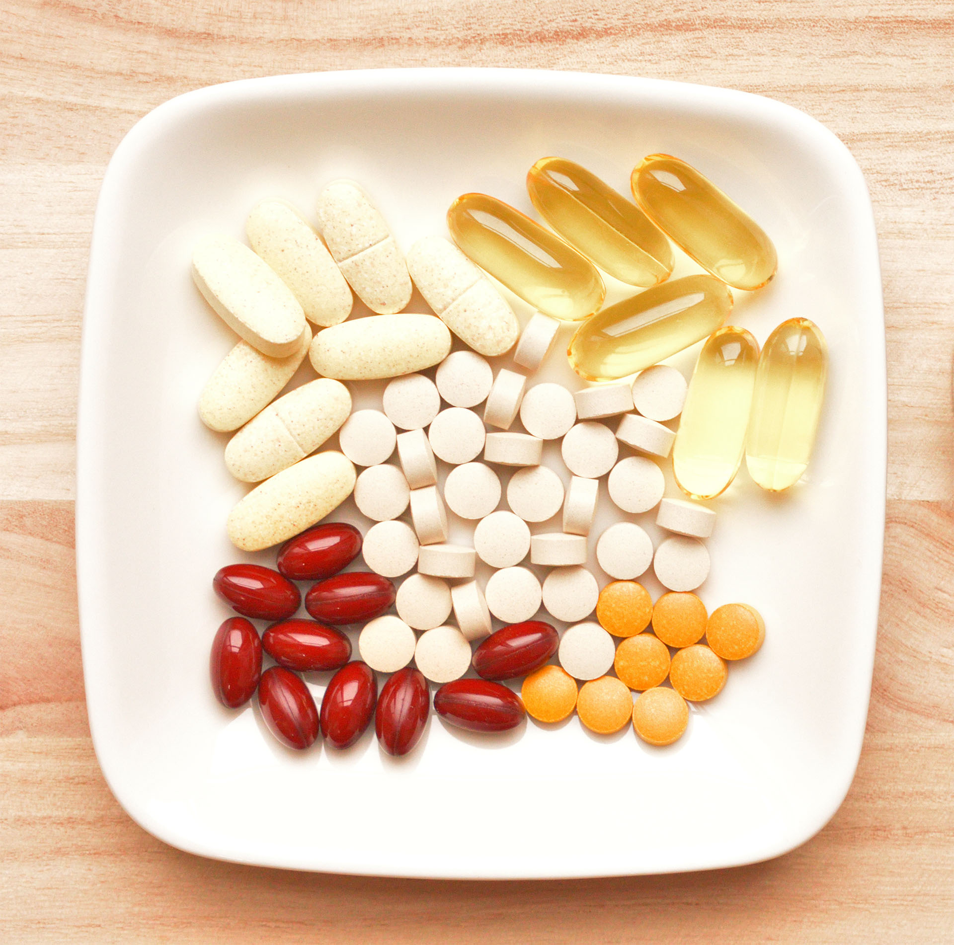 A plate filled with assorted pills and vitamins, representing various food supplements for health and wellness.