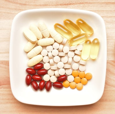 A plate filled with assorted pills and vitamins, representing various food supplements for health and wellness.