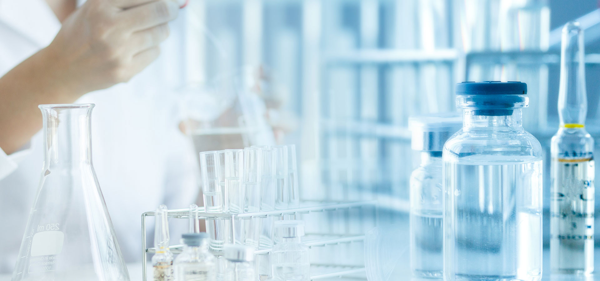 Laboratory glassware, including test tubes, vials, and flasks, with a pipette in use, illustrating sample preparation in a controlled lab environment.