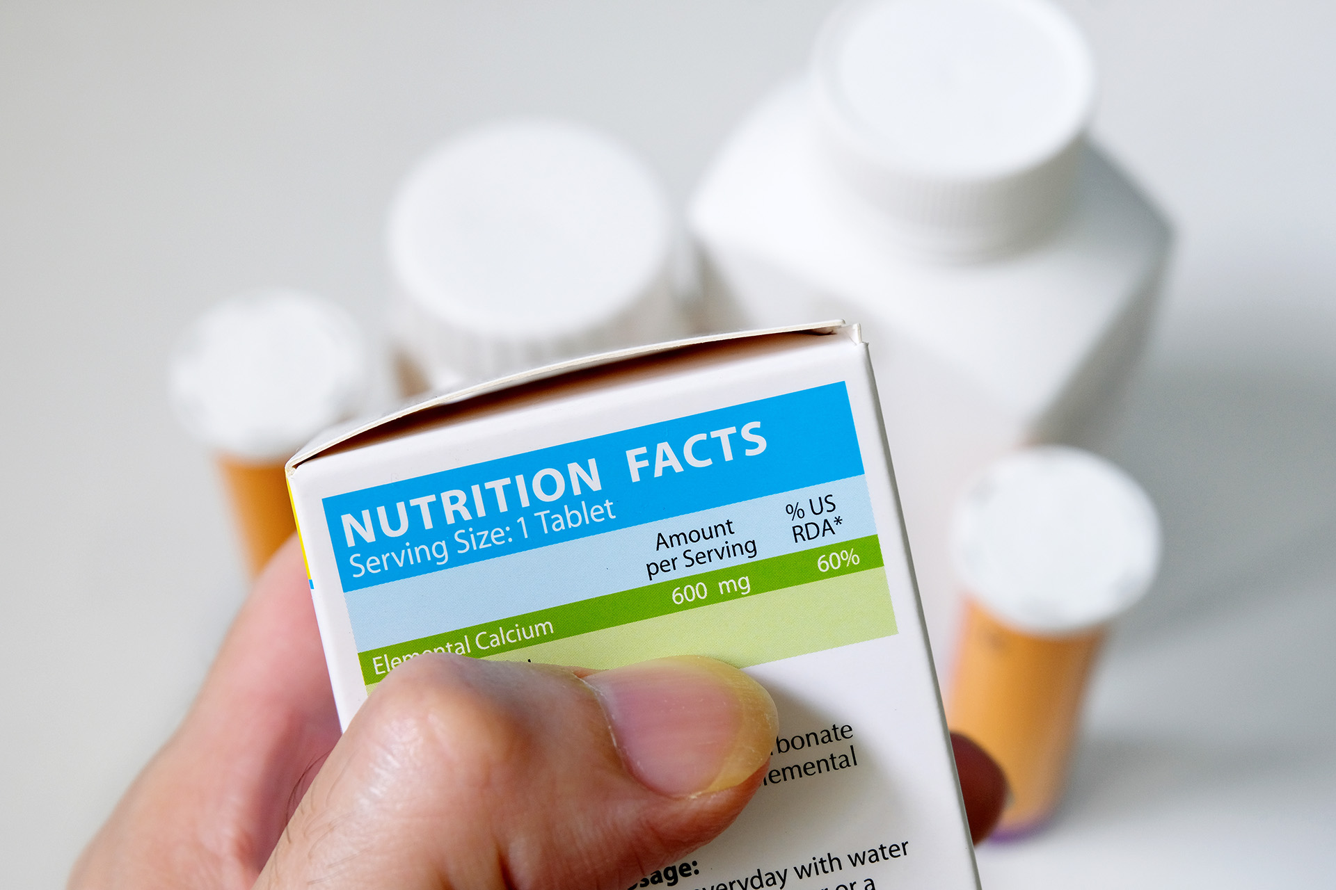 Hand examining a nutrition facts label on supplement packaging to assess nutritional information.